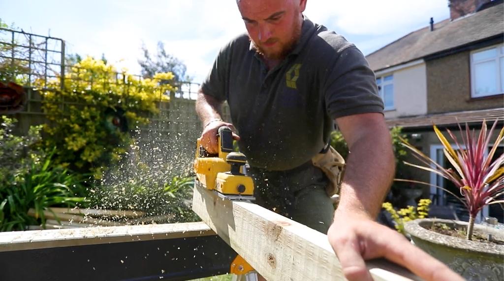 Sean Doyle planing a timber joist on site with a cordless planer