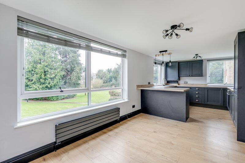 Open-plan living space with light oak engineered flooring and a large garden-facing window