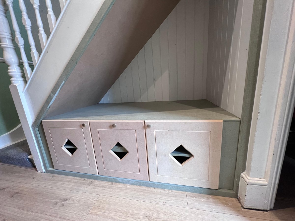 Bespoke under-stairs storage in primed MDF with three diamond-cut drawer fronts and a padded seating top